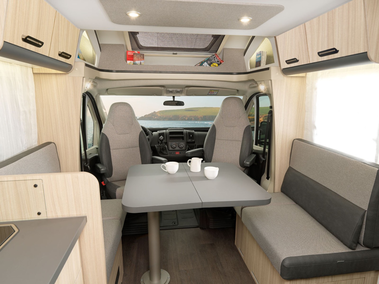 Dinette van de Sun Living S72DL camper, met twee banken en een centrale tafel, omringd door lichte bekleding en royale ramen voor natuurlijk licht